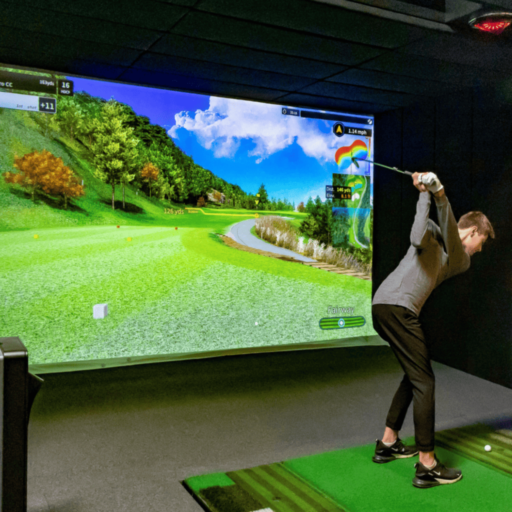 A full time golf academy students hits shots into our Golfzon GDR training simulator