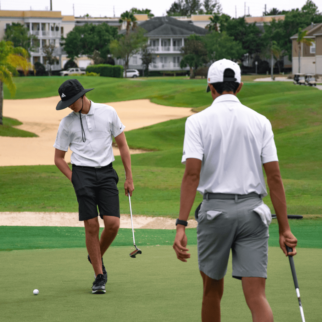 two junior golf program students reading putts on a golf green
