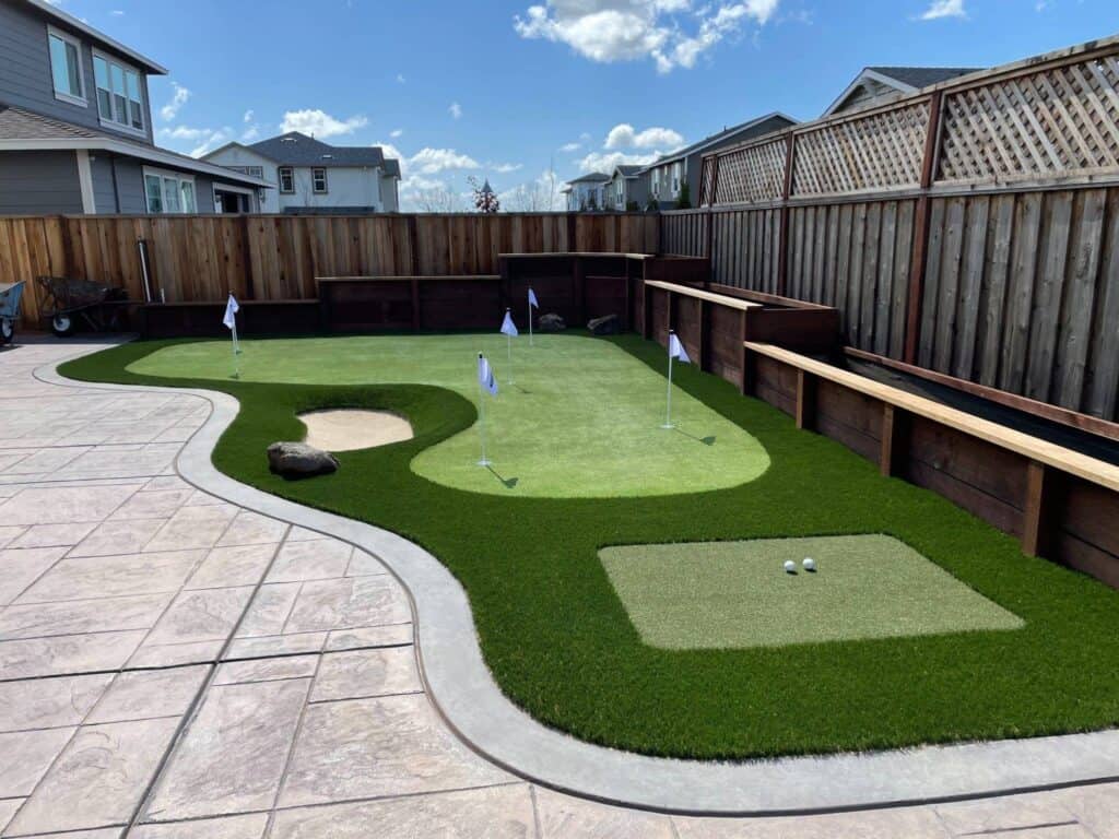 A beautifully kept DIY backyard golf green sits in the sun